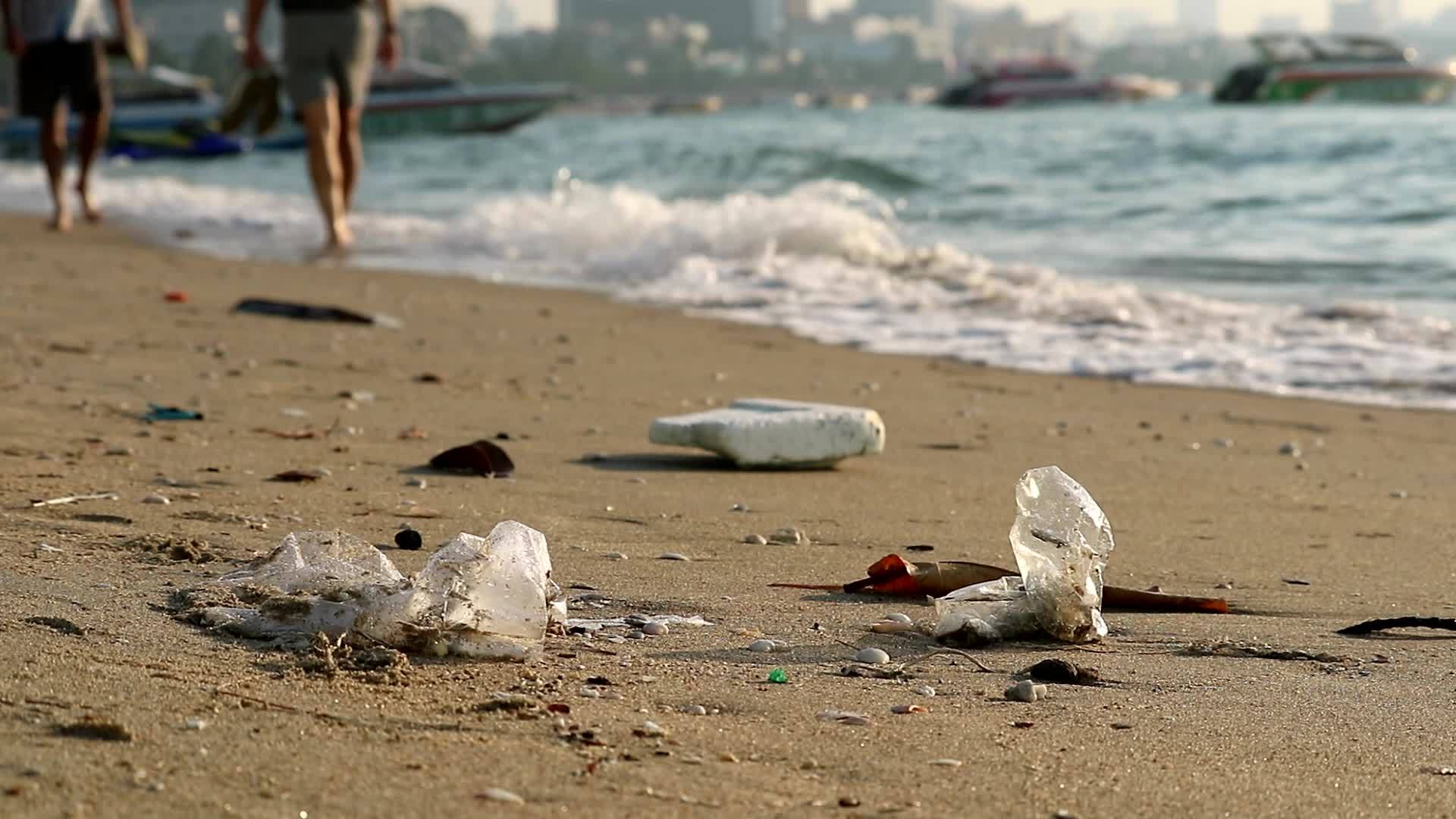 人们用塑料橡胶在海滩上行走废物留在海滩上海浪把它们放在海滩上视频的预览图
