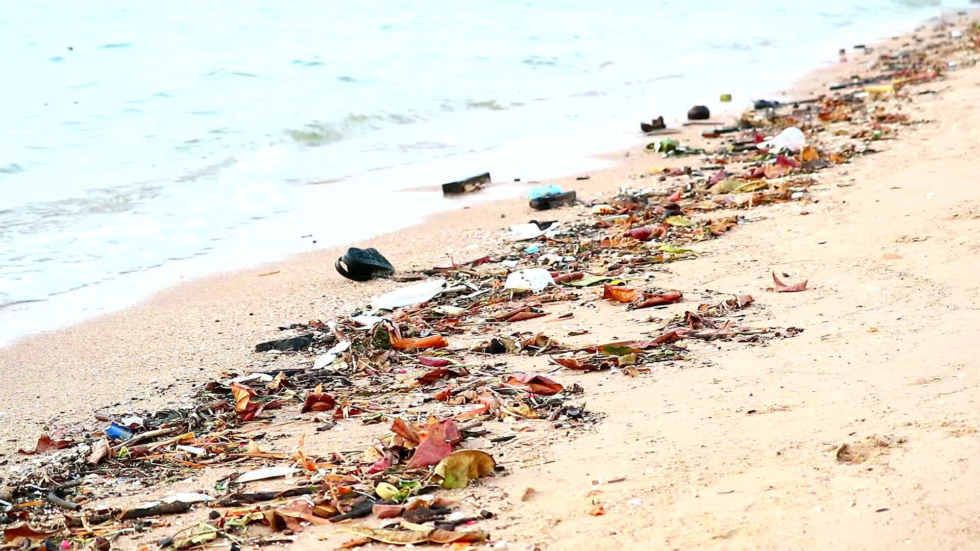 日落塑料橡胶和沙滩上的废物留在沙滩上海浪把它吹进海里视频的预览图