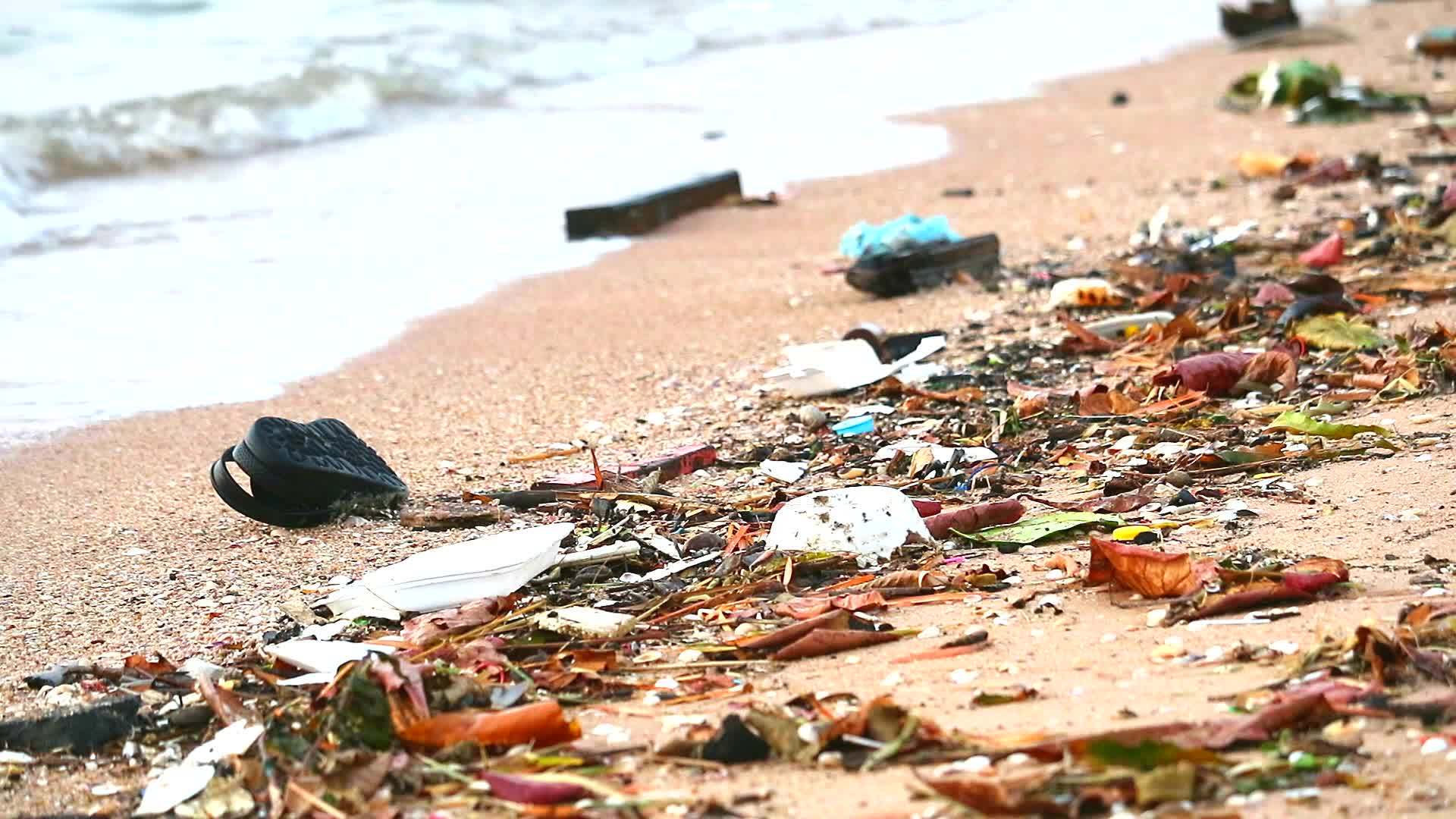 日落塑料橡胶和沙滩上的废物被扔在沙滩上海浪把它们吹进海滩视频的预览图