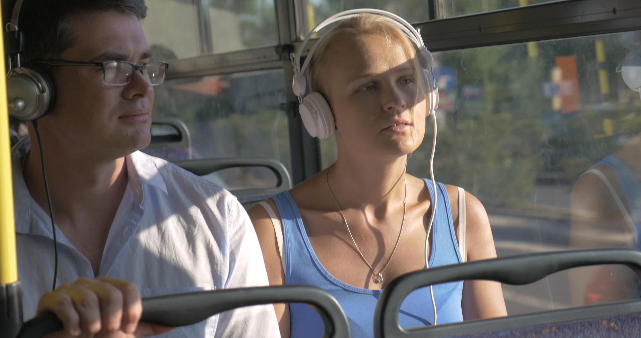 公共汽车旅行时男女在耳机里听音乐视频的预览图