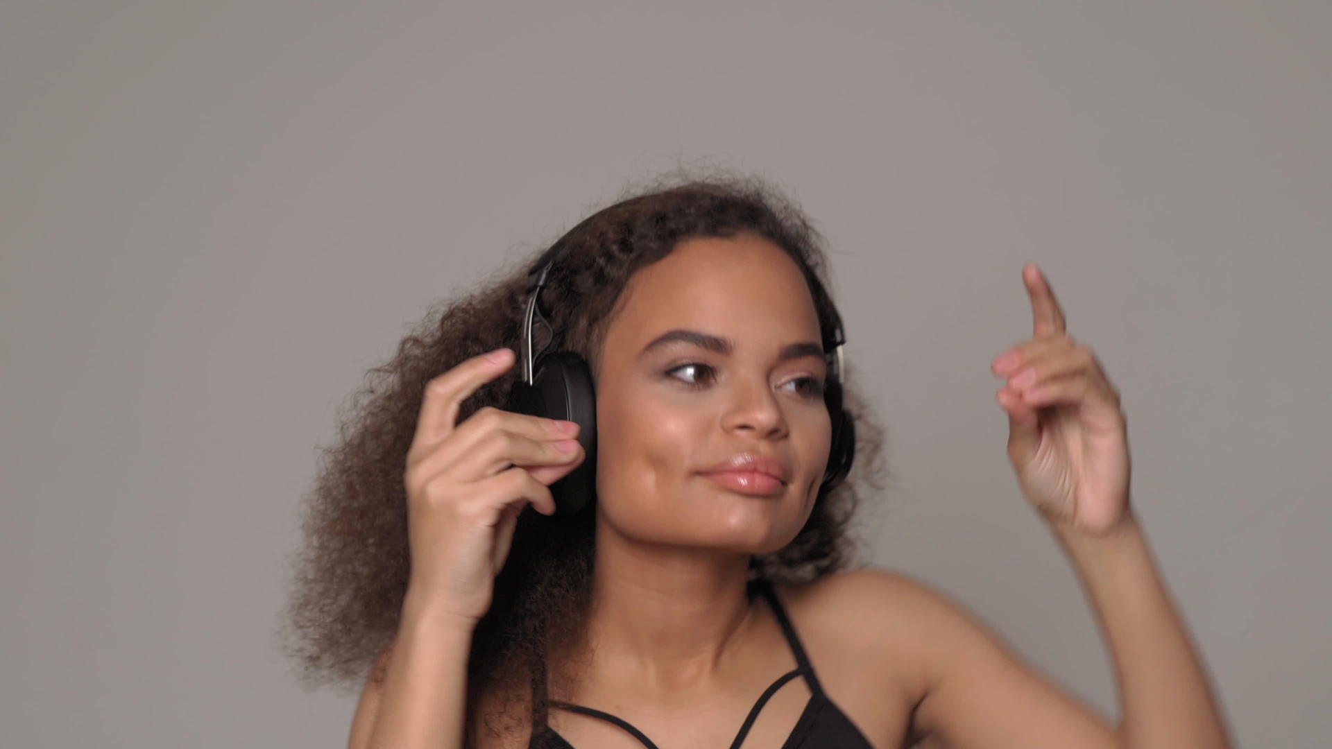 感受节奏舞蹈年轻的非裔美国女孩戴着耳机和黑色外套视频的预览图