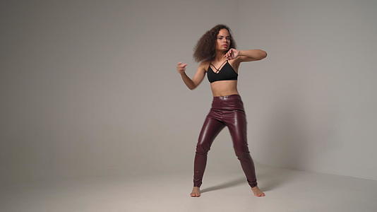 年轻的非裔美国女孩穿着黑色外套和皮裤双手在空中跳舞视频的预览图