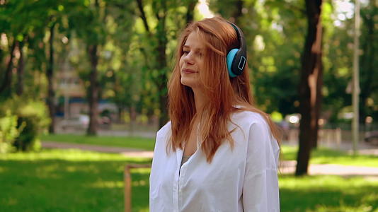 女性用耳机听户外音乐视频的预览图