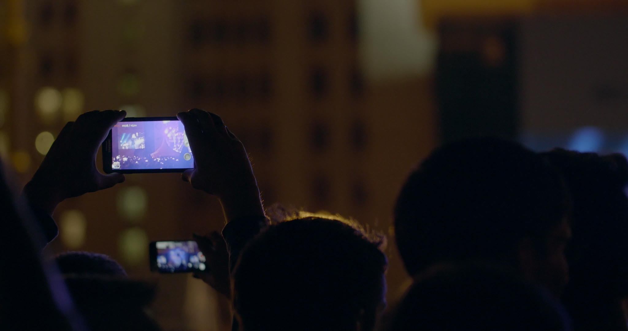 在户外音乐会上舞台和大屏幕的视频被智能手机录制视频的预览图