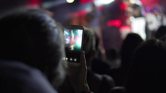 女孩在现场音乐会上用相机和手机拍照和录制智能手机记录视频的预览图
