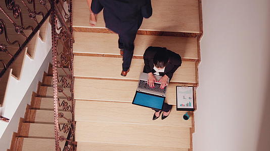 女性在办公楼梯上用笔记本电脑超负荷工作视频的预览图