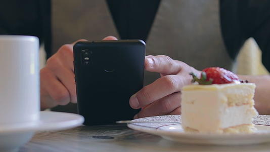 顾客在咖啡店休息时使用智能手机视频的预览图