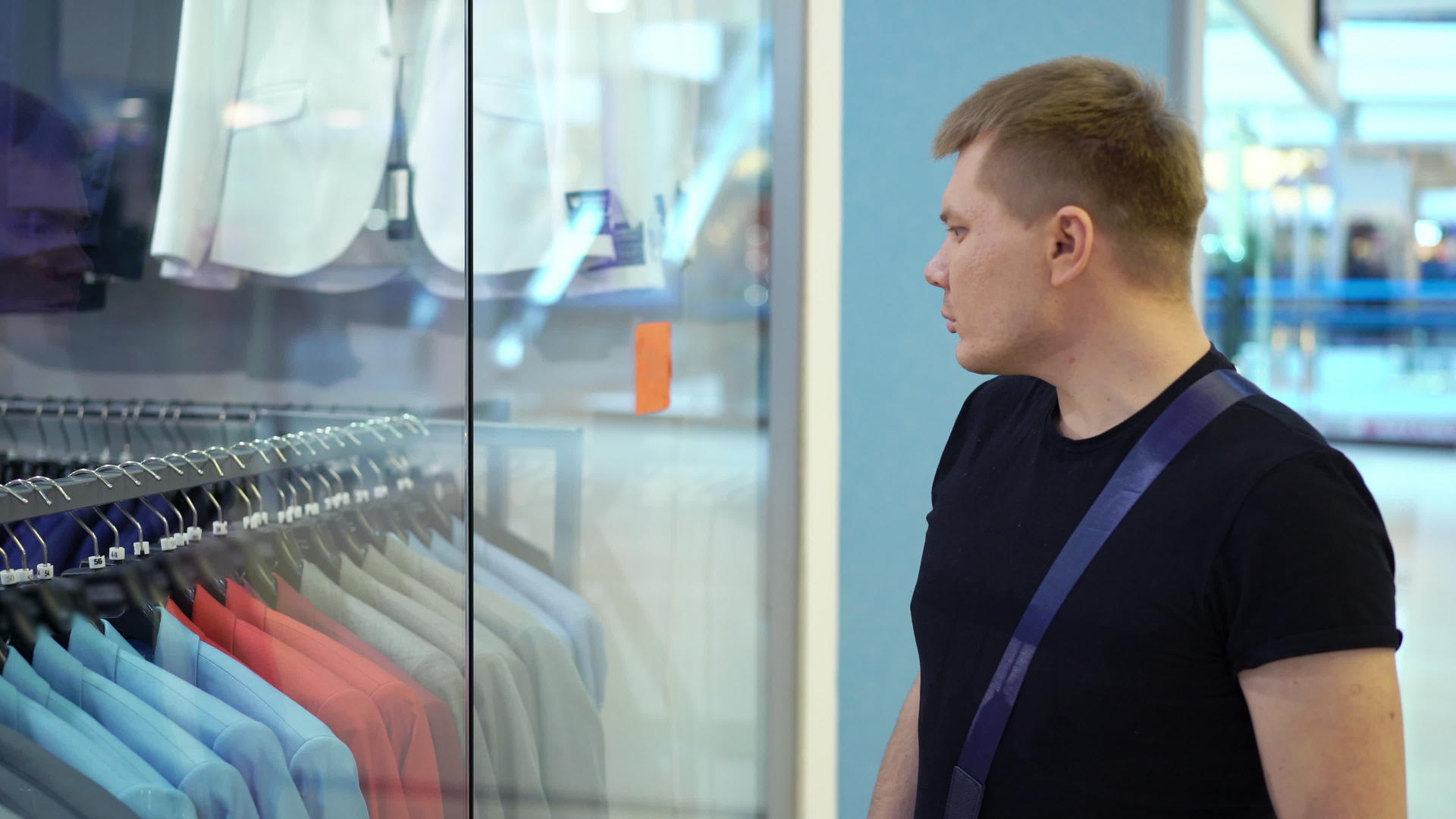 年轻迷人的男人在商场和男人的西装里看着商店的窗户视频的预览图