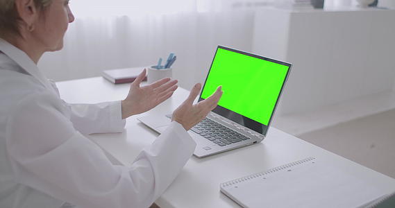 女医生正在和医生预约在线查看笔记本电脑的绿色显示屏视频的预览图