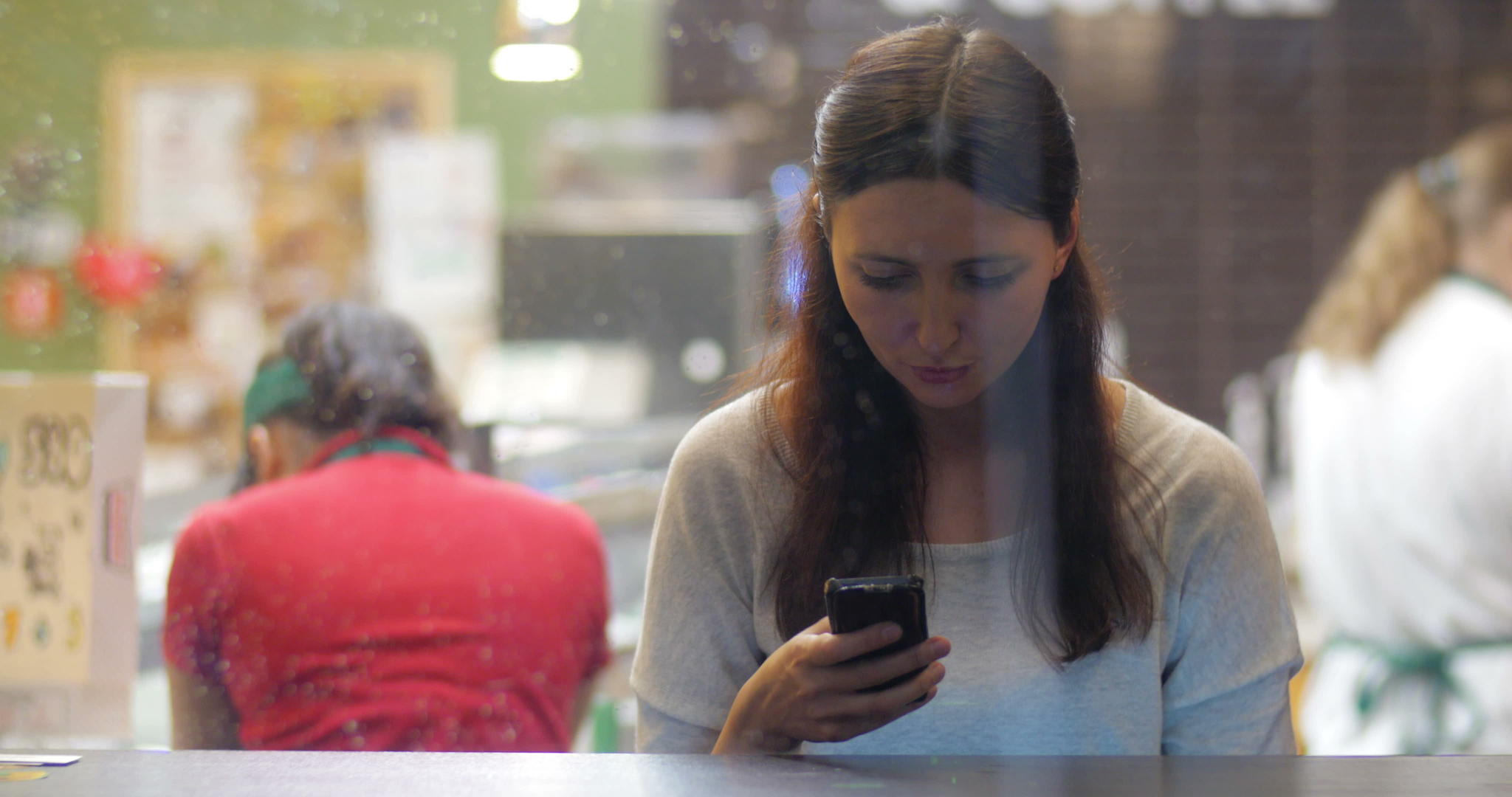 咖啡馆里有智能手机的年轻女孩视频的预览图