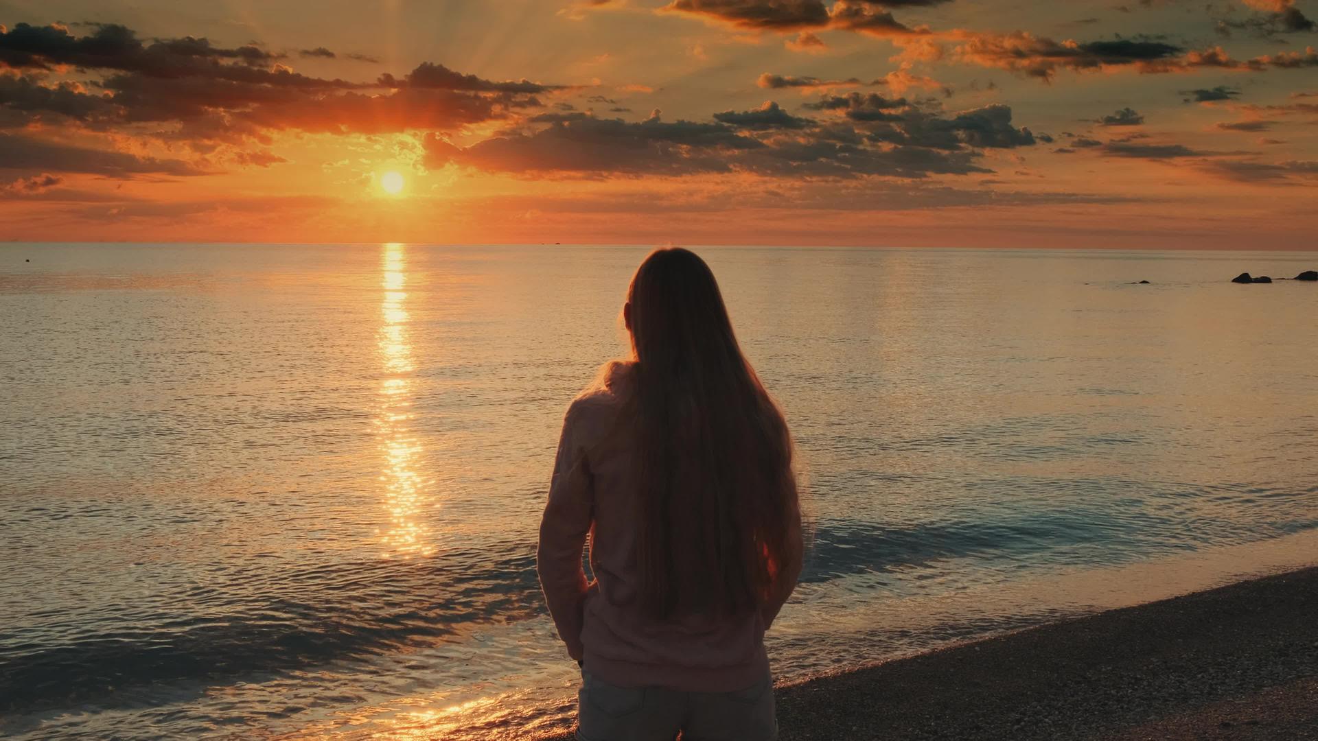 女性用伸展的手臂享受海中日落的美丽视频的预览图