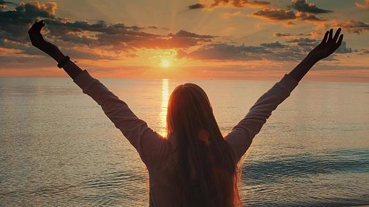 年轻女子手臂伸展享受中日落的美景视频的预览图