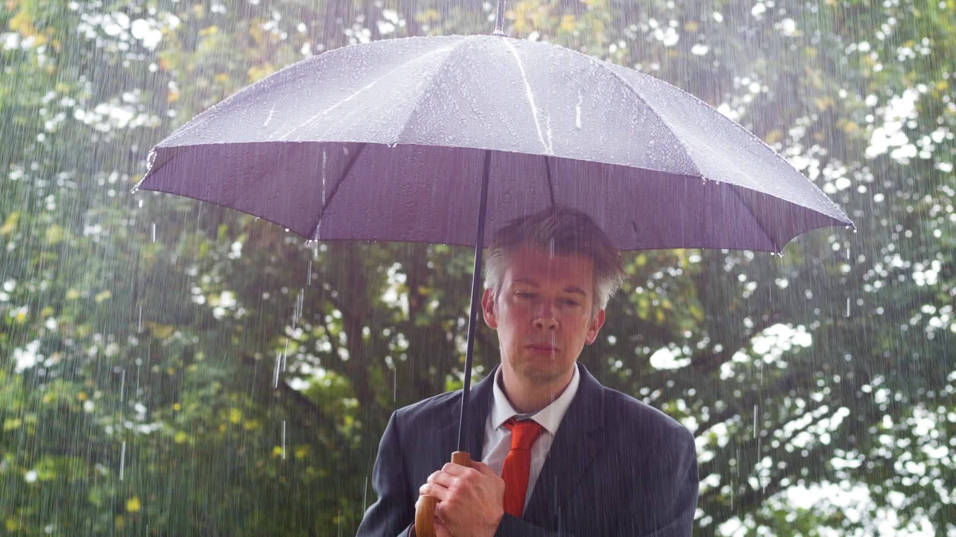 商人躲在伞下躲在雨伞下视频的预览图