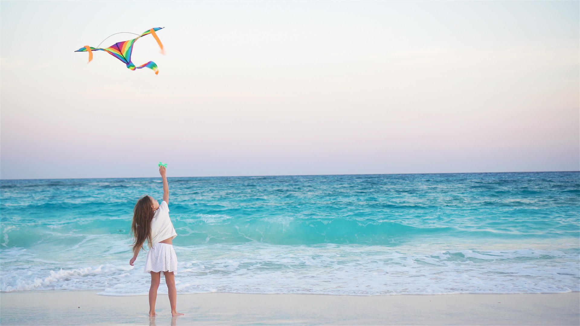 日落时在热带海滩放风筝的小女孩在海滩上玩耍视频的预览图