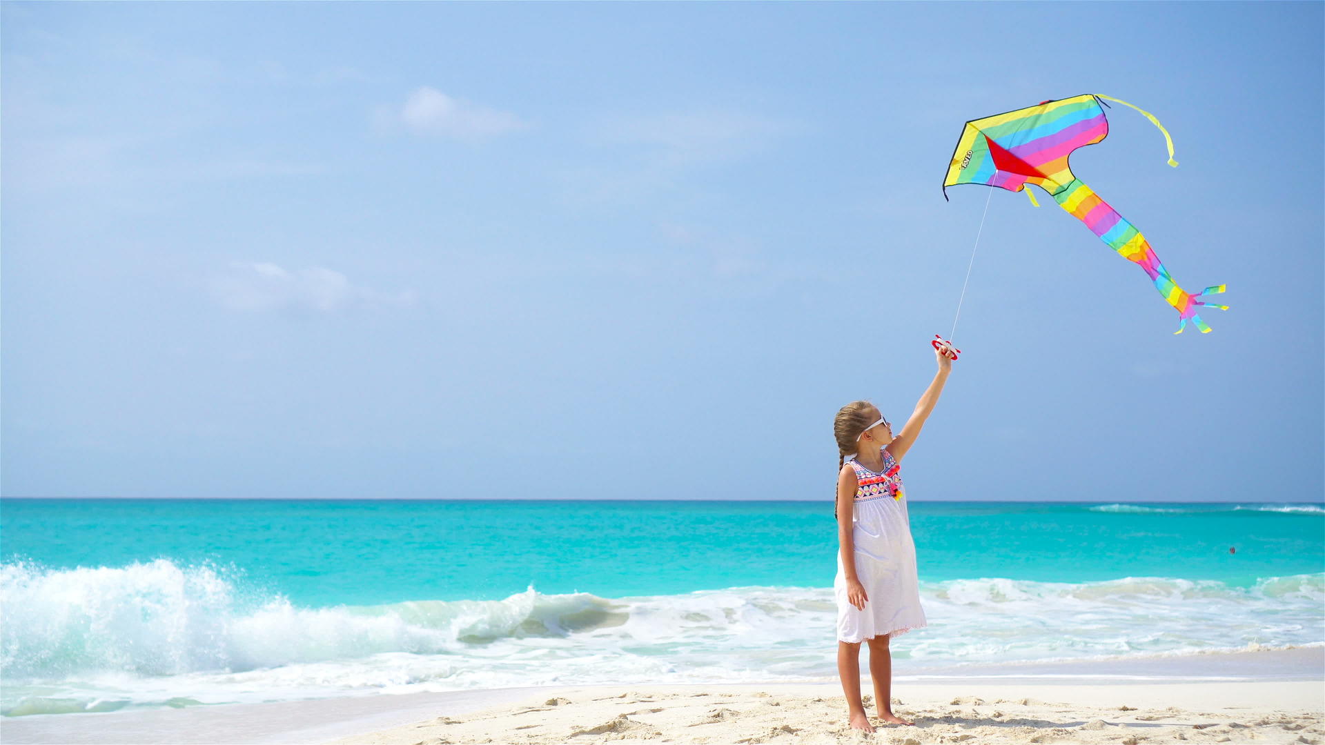 在热带海滩放风筝的小女孩在海滩上玩沙滩玩具视频的预览图