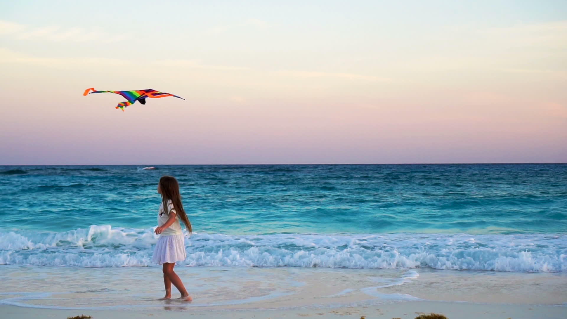 可爱的小女孩在热带海滩上放风筝孩子们在海边玩日落视频的预览图