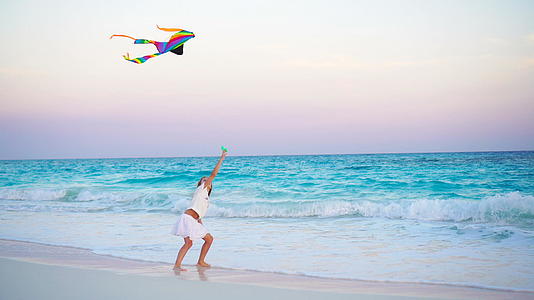 可爱的小女孩在热带海滩上放风筝孩子们在海滩上玩得很漂亮视频的预览图