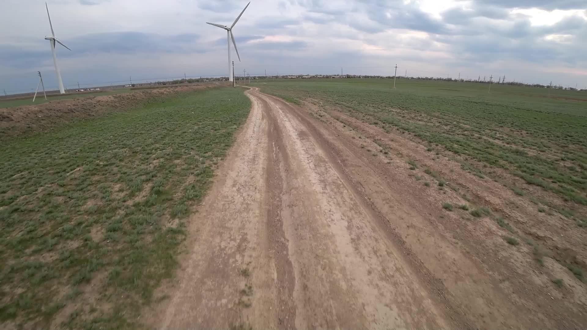 骑自行车沿着风车行驶在一条灰尘小路上视频的预览图