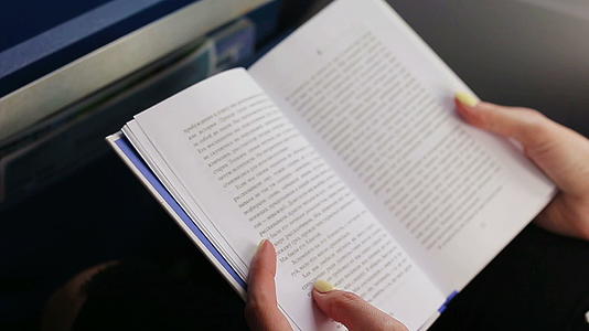 女人乘飞机在飞机窗口旅行和阅读书籍视频的预览图