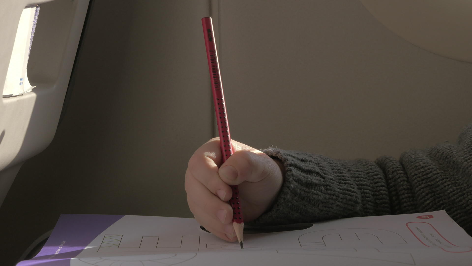一个小男孩坐在飞机上用纸上的铅笔画画视频的预览图