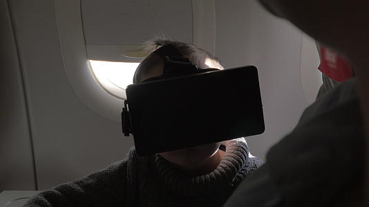 飞机上坐着一个戴着虚拟现实眼镜的小男孩视频的预览图