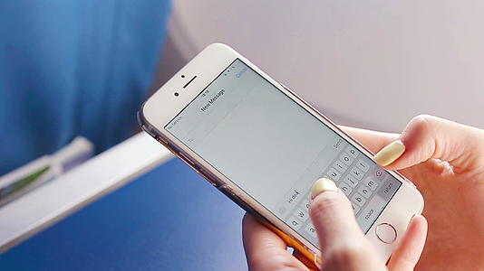 女性在飞行中用手机发送短信飞机背景窗口的特写显示视频的预览图