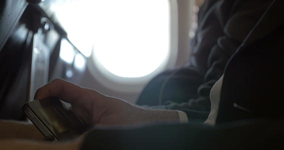 男子在飞机上用智能电话看电影视频的预览图