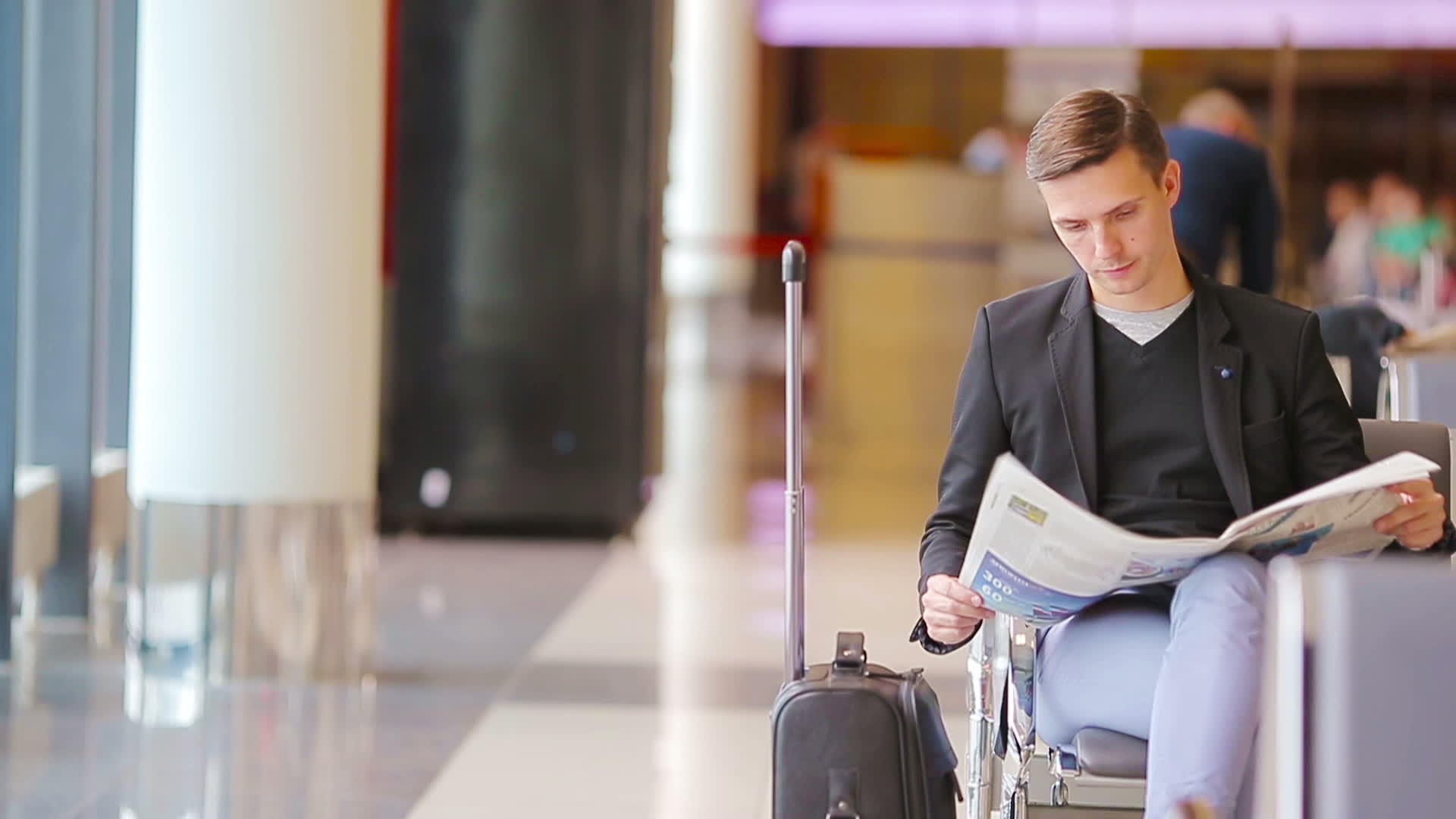 年轻的白人男子在机场等待登机时拿着报纸穿着西装视频的预览图