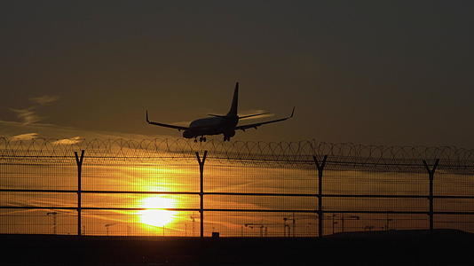 飞机在阳光下降落太阳在阳光下机场的轮廓慢慢移动视频的预览图