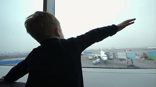 小男孩用手看着飞机看着窗外的窗户视频的预览图