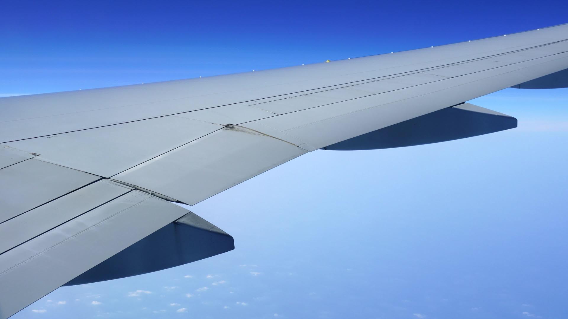 城市上空的特写机翼飞机在蓝天上飞行视频的预览图