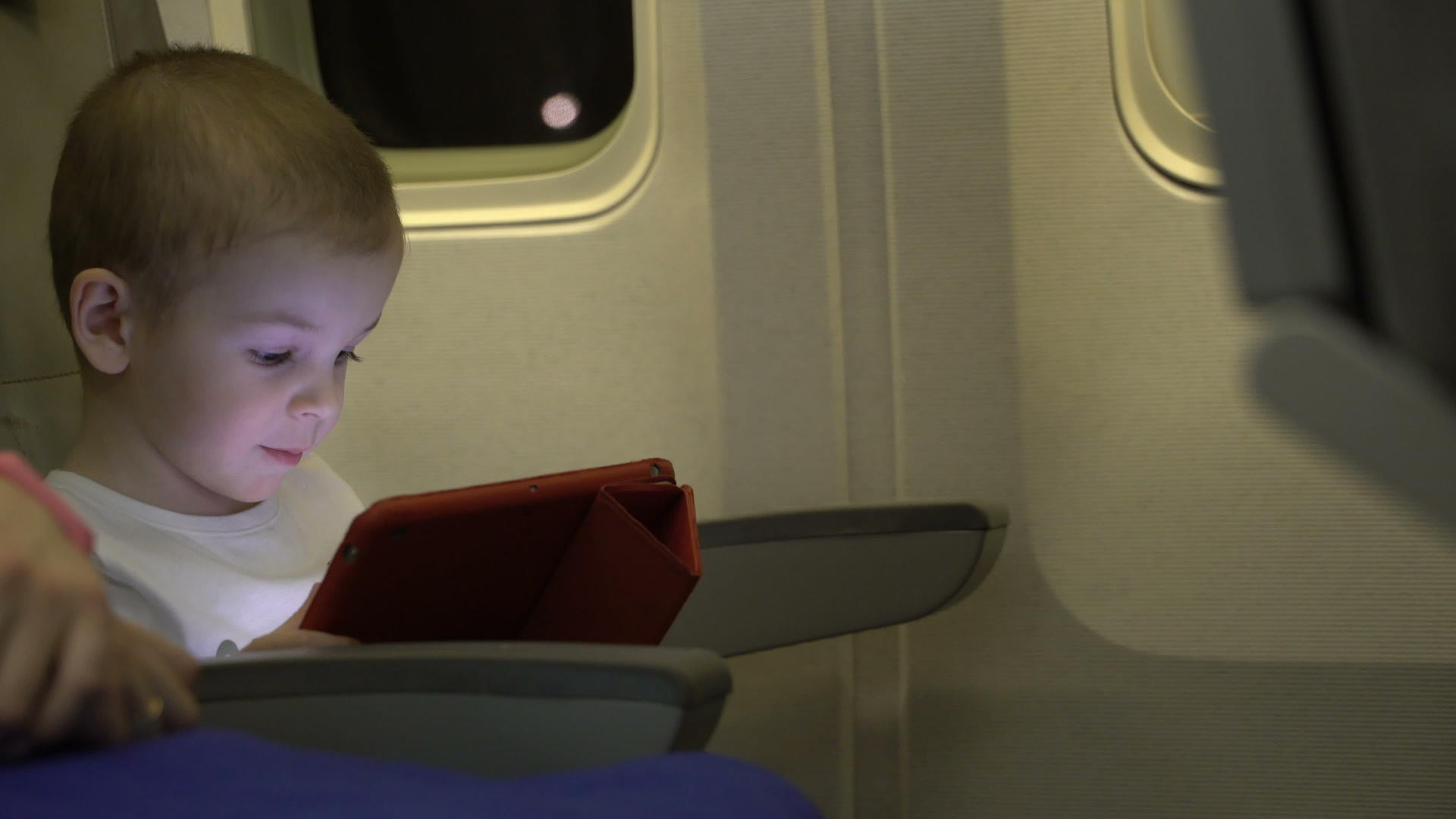 两岁的男孩正在玩平板电脑坐在飞机座椅上视频的预览图