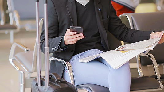 男性手中的特写智能手机和机场报纸穿着西装和外套视频的预览图