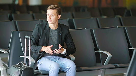 城市商人谈论智能手机在机场旅行穿着西装和外套视频的预览图