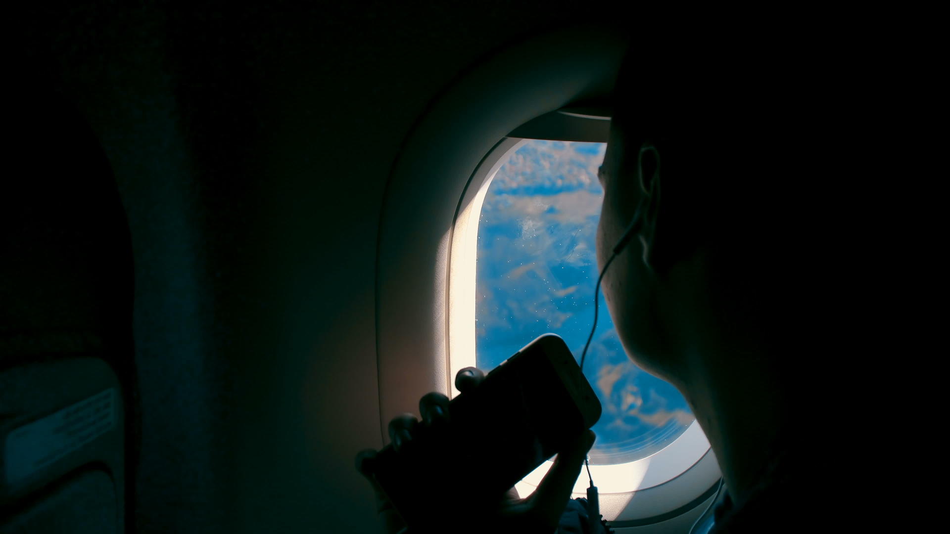 亚洲女孩用耳机听音乐用智能手机拍照微笑着看飞机窗口视频的预览图