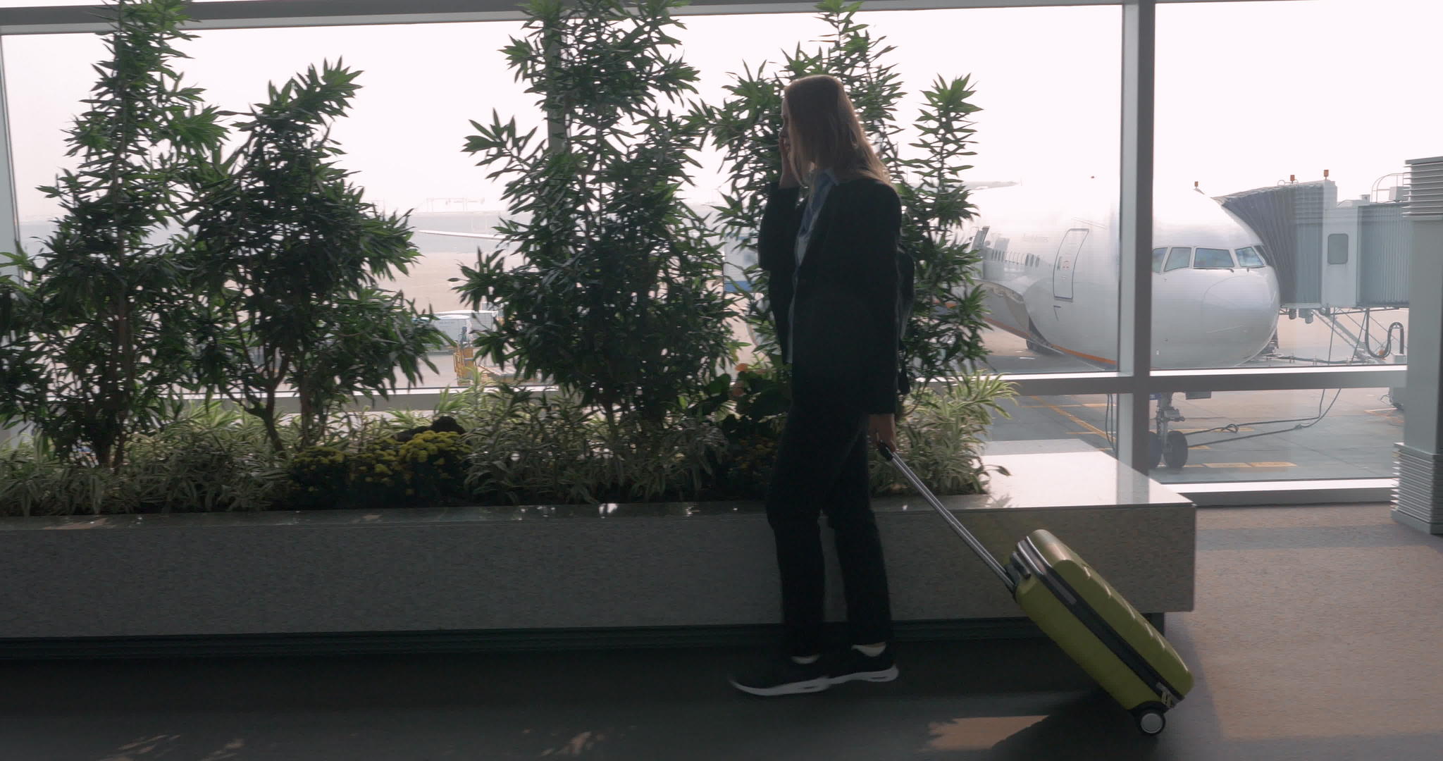 女人在电话里用手提箱说话在机场车站走路视频的预览图