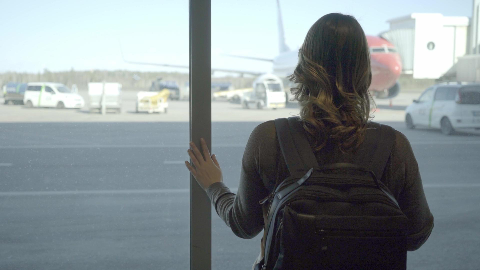 机场的年轻旅性透过飞机的窗户看着飞机视频的预览图