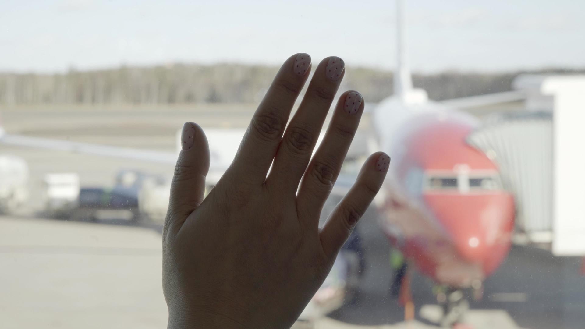 机场的年轻旅性透过飞机的窗户看着飞机视频的预览图