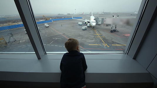 小男孩看着机场窗外的小男孩视频的预览图