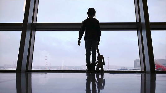 在等待登机时机场大窗附近的小女孩正在等待登机视频的预览图