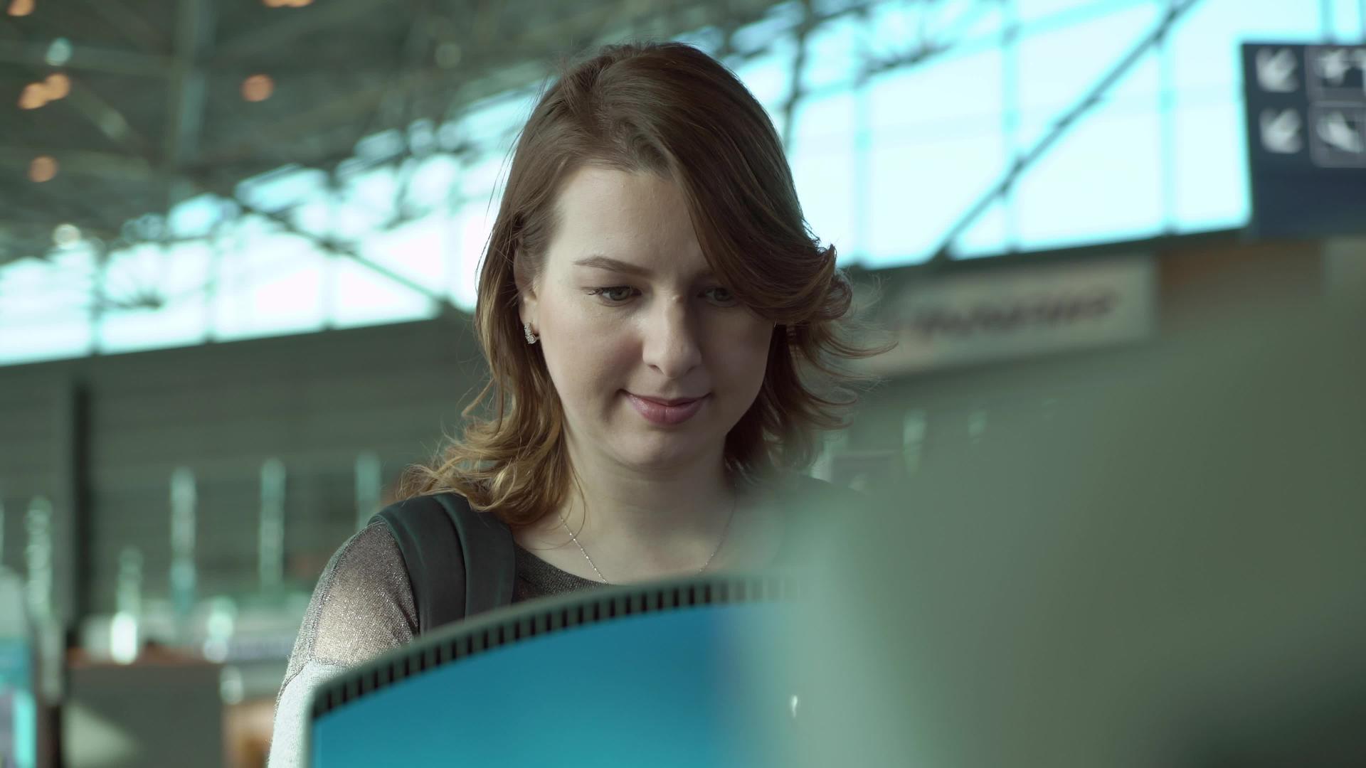 自助中转区的年轻女性在机场航站楼拥有带有触摸屏的自动机器视频的预览图