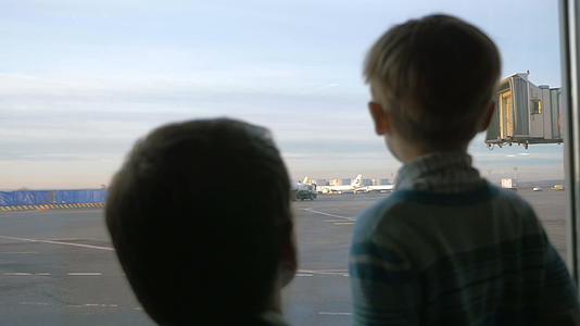 父亲和儿子看着机场窗外的窗户视频的预览图