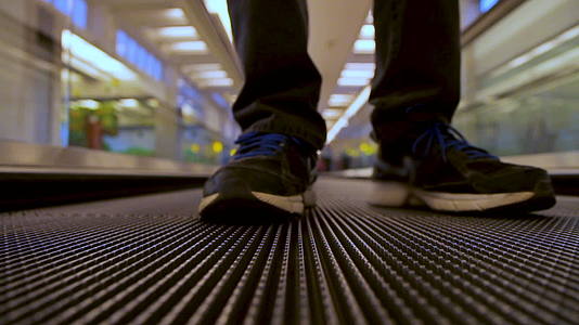 在机场终点站男子的腿和行人使用移动平面扶梯视频的预览图