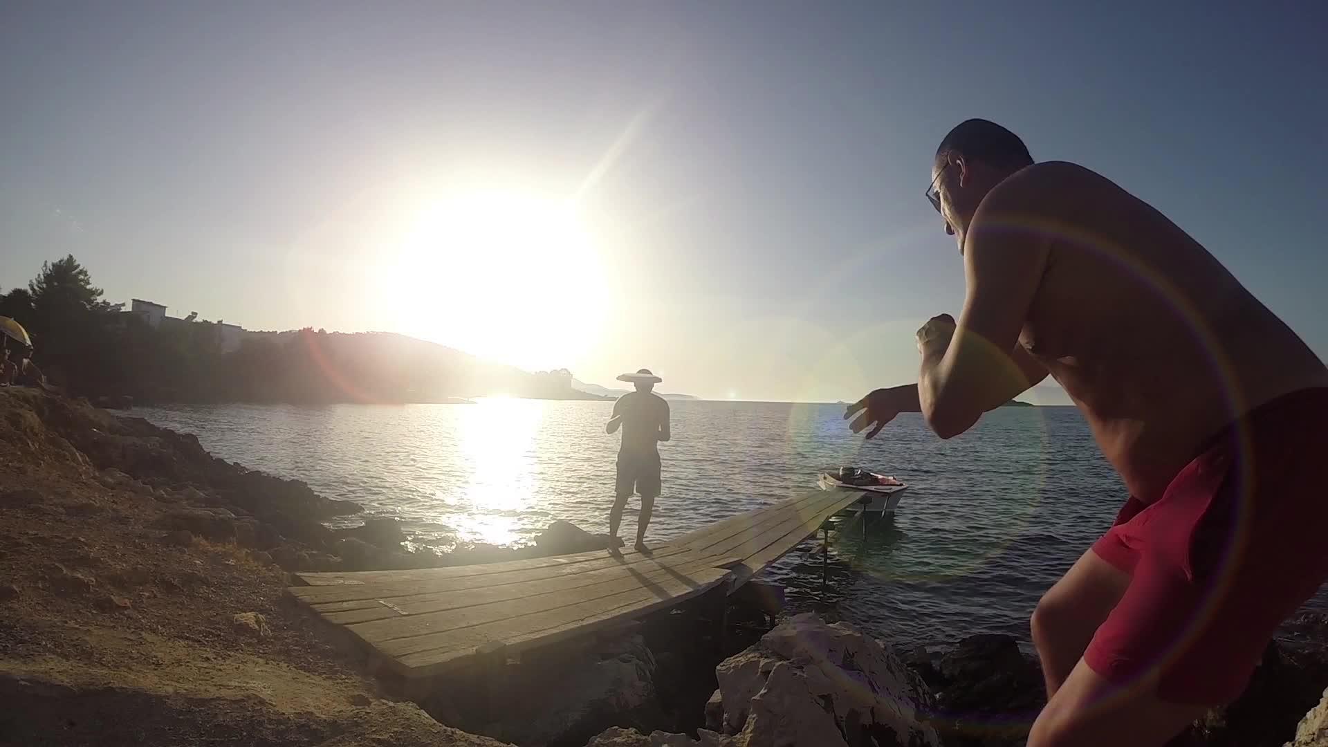 两个男人在热带海滩上玩飞盘对抗山后的日落视频的预览图