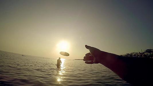 日落时在海滩上玩飞盘的人慢动作视频的预览图