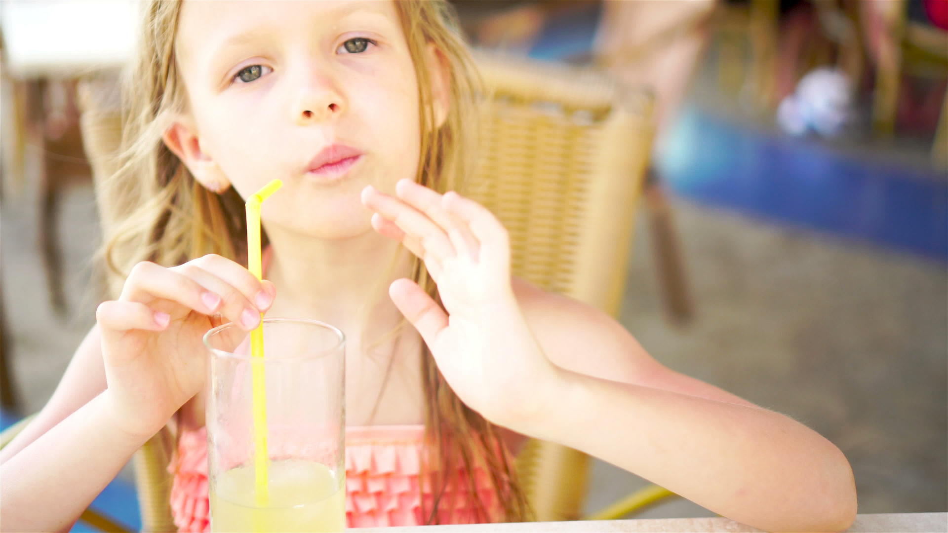可爱的小女孩坐在晚餐桌旁喝着新鲜的果汁视频的预览图