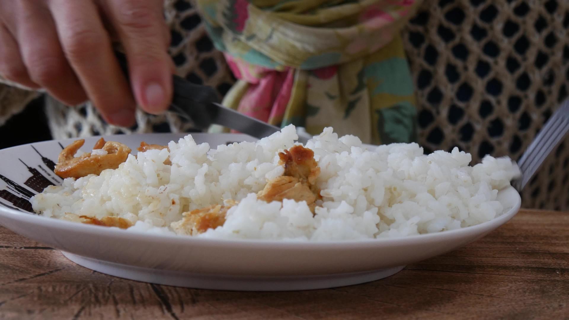 手紧的女人拿着叉子和米饭盘子里的肉视频的预览图