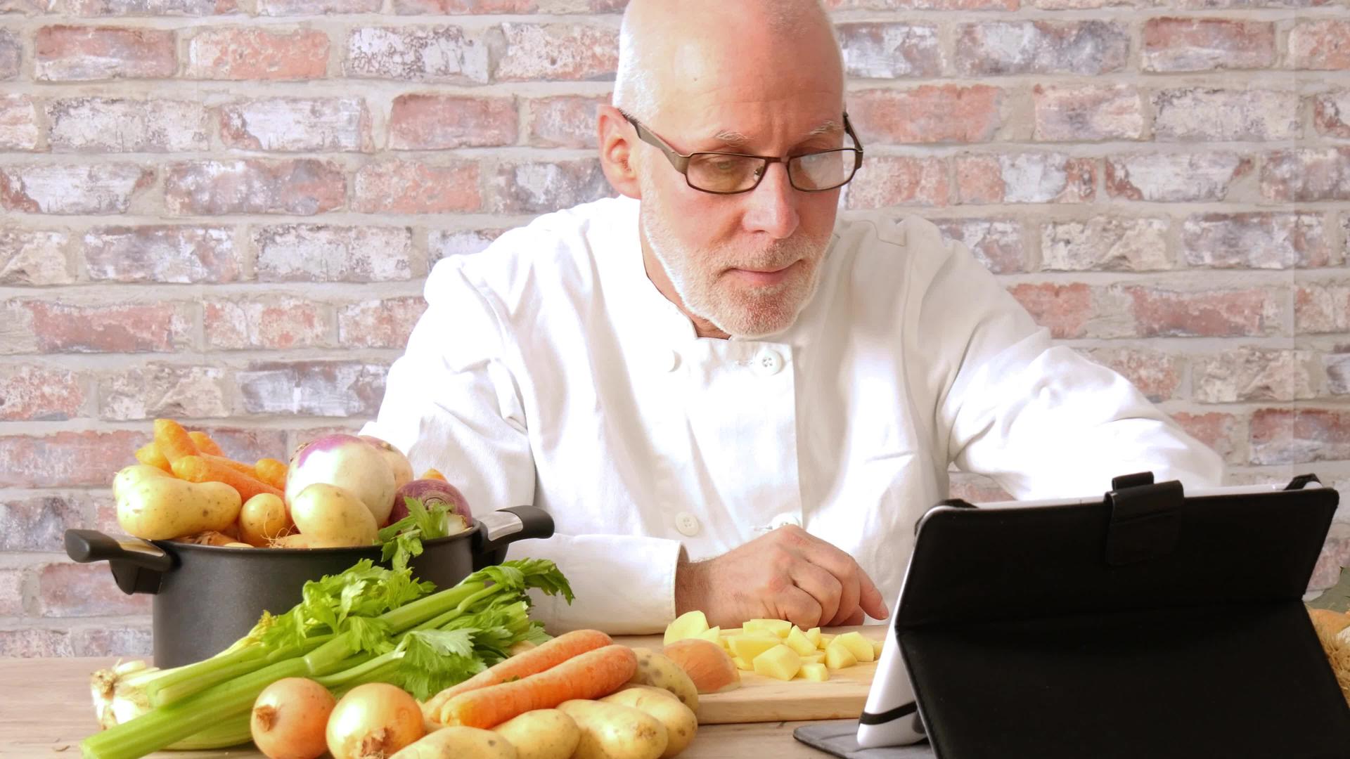 男人在厨房做饭用数字平板电脑视频的预览图