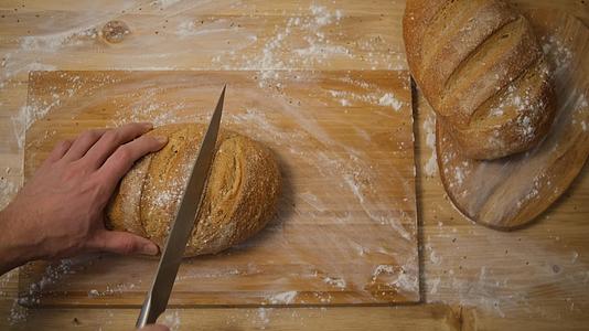 一个男人在厨房里切面包把面包切成薄片做成三明治顶视图视频的预览图