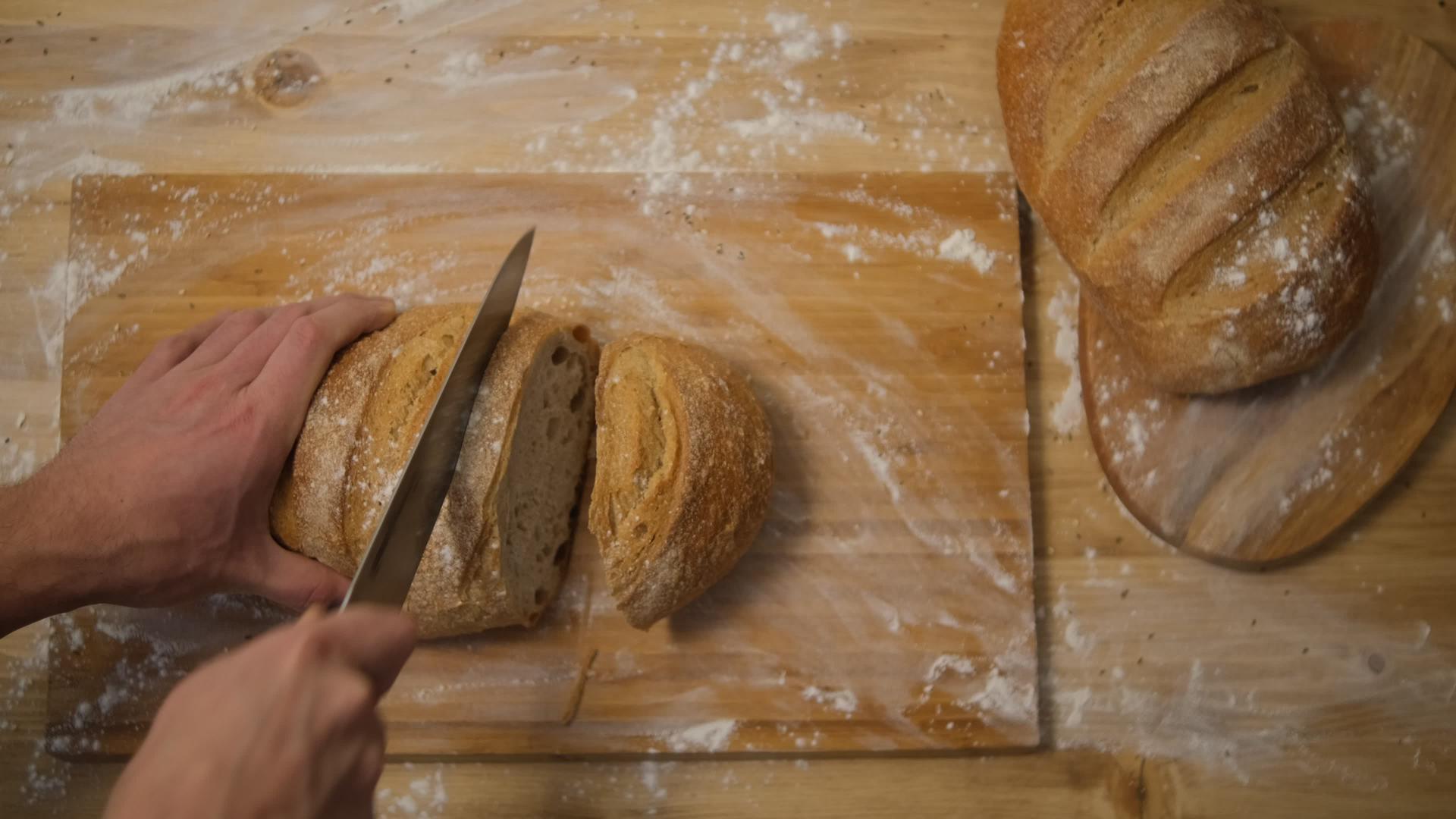 一个男人在厨房里切面包把面包切成薄片做成三明治顶视图视频的预览图